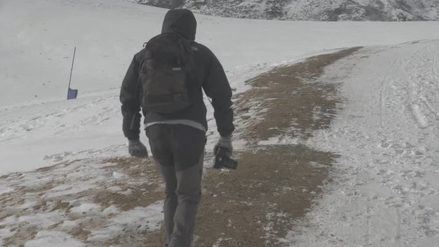 Photographer walking and taking photos in snowy montains. Footage taken with Panasonic Lumix Gh5.