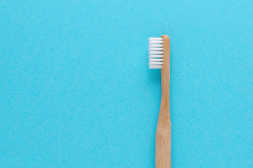 wooden toothbrush on blue background with copy space