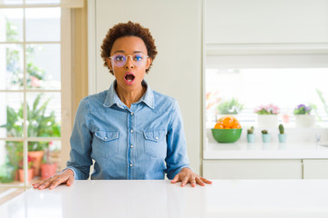 Young beautiful african american woman wearing glasses afraid and shocked with surprise expression,...