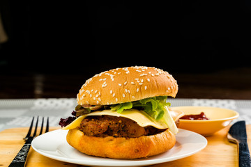 Homemade chicken burger with cheese and vegetable in white plate
