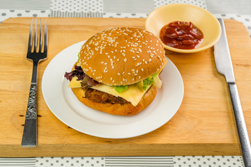 Chicken burger with cheese and vegetable is ready to eat in a white plate
