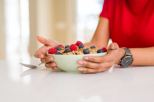 Close up of young woman eating healthy cereals and berries for breakfast
