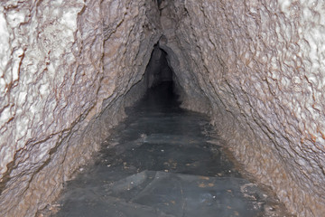 Triangular passage with an ice floor in a karst cave “North Venice”. Pinega Nature Reserve, Arkhangelsk region, Russia