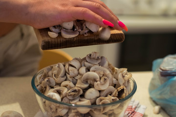 Woman chopping mushrooms with knife on cutting board.
