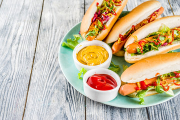 Homemade hot dogs with fresh greens, sausages and sauces, white wooden background copy space top view