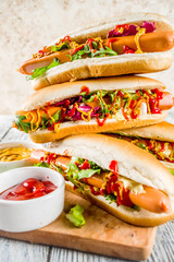 Homemade hot dogs with fresh greens, sausages and sauces, white wooden background copy space top view