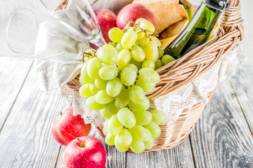 Picnic basket with food and drinks (fresh fruits, bread and wine bottle, glasses), copy space