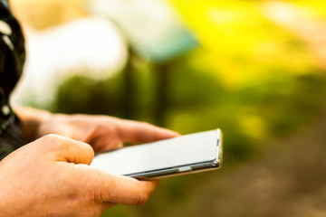 Male holding a smartphone in a summer garden, park, warm, bokeh phone, hand.