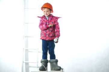 Little girl electrician in a construction helmet with a light bulb.