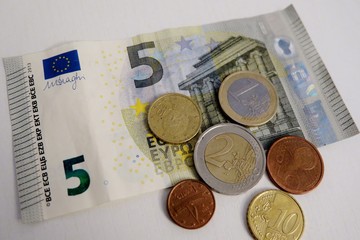 five euro and a penny on a white background close-up
