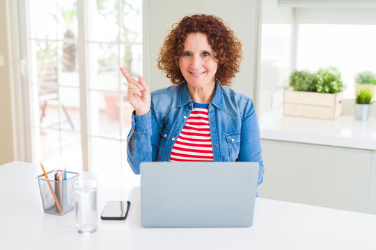 Senior woman working using computer laptop very happy pointing with hand and finger to the side