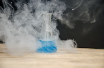flask with blue liquid in smoke over black background. chemical analysis