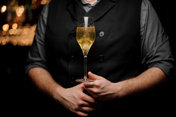 Close-up of glass with sparkling wine in bartender's hands