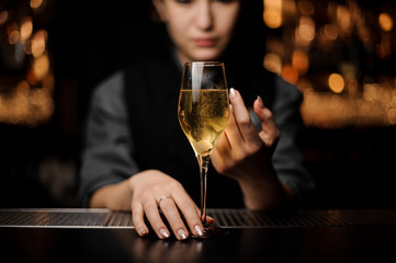 Close-up of the glass with sparkling wine in a bartender's hands