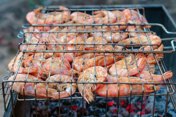 Tasty shrimps are cooked on the fire on a wire rack. Grill seafood cooking.