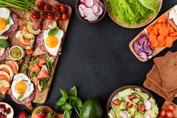 Appetizers table with healthy snacks. Brushetta or sandwich set on the board over black concrete background. Top view, flat lay