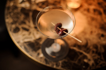 Close-up of an alcohol cocktail with olives on table
