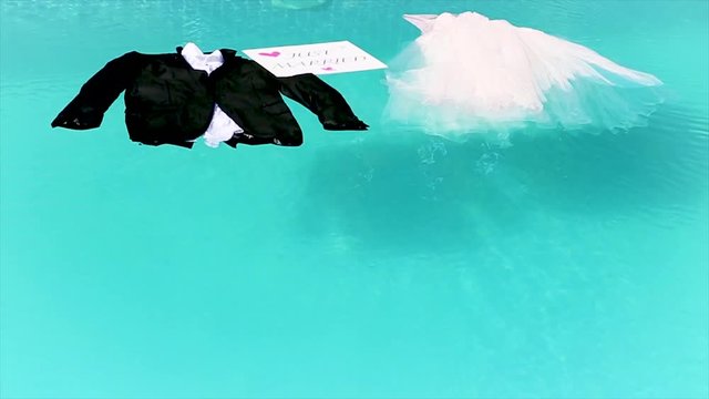 bride and groom's clothes are in the pool with just married sign