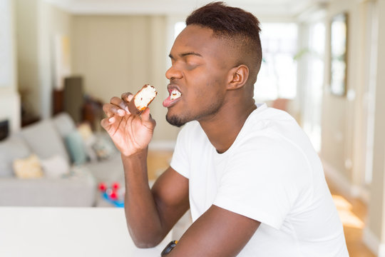 African american man eating  and enjoying a sweet chocolate donut