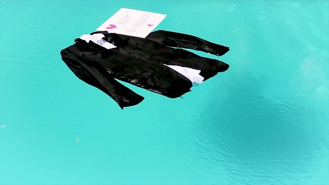 Clothes of the groom is swiming in the pool with a sign saying Just Married.