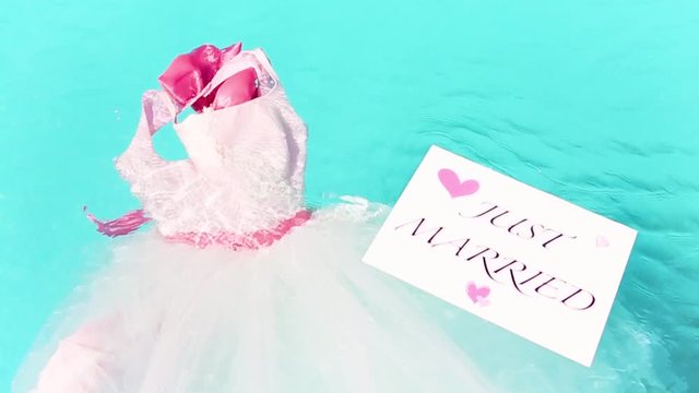 Wedding dress in the pool with Just Married Sign.
