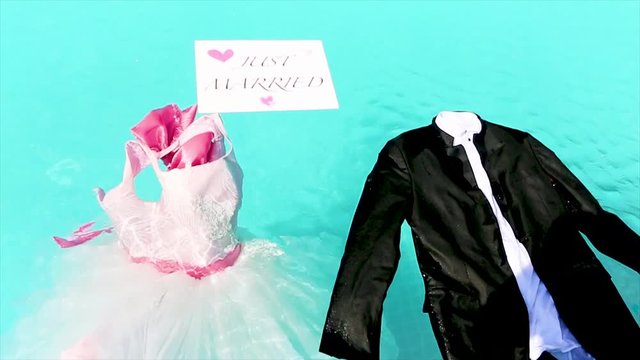 bride and groom's clothes are in the pool with just married sign