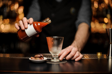 Bartender mixing alcohol cocktail with bloody mary in the bottle