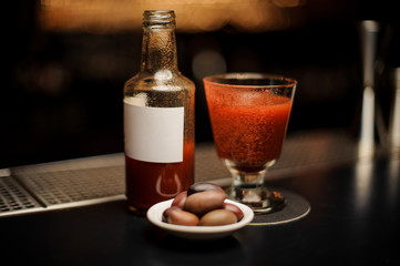 Close-up of bloody mary cocktail in glass with bottle and plate