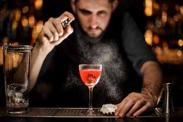 Bartender pours the alcohol cocktail using sprayer