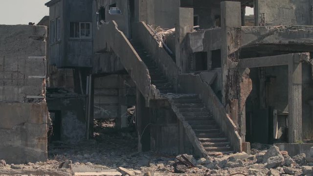 Damaged and partly destroyed look at concrete stairs linked to damaged buildings on Hashima Island, commonly called Gunkanjima, Nagasaki, Japan