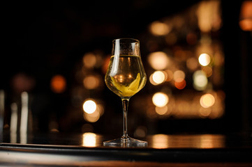 Close shot of alcohol cocktail with lemon rind on counter