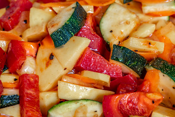 Raw fresh vegetables cut for further processing, mixed and topped with an oily spice mixture.