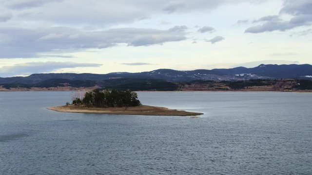Aerial view of isolated small forest island in a lake with birds