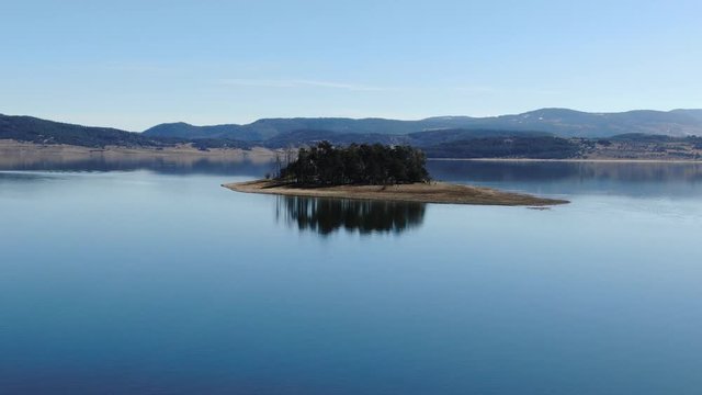Aerial view of isolated small forest island in a lake with birds