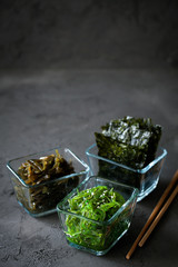 Traditional Japanese Chuka Wakame seaweed salad and crispy roasted nori sheets in glass bowl on dark background top view with copy space.Asian japanese chuka.Organic natural product.Raw vegan food © daarnautova