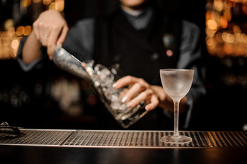 Female bartender adds ice in glass with ice scoop