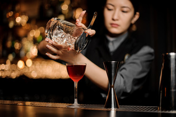 Bartender pouring alcohol cocktail with a strainer