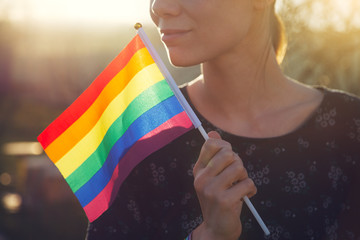 happy young smiling woman with rainbow ribbon wristband on her hand holding lgbt colorful rainbow...