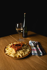 Bodegon of macaroni dish with bolognese sauce and grated cheese and a glass of accompanying wine.