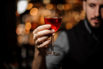 Close-up of bartender holding cocktail with orange rind