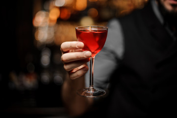 Close-up of an alcohol cocktail with orange rind in bartender's hand