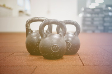 Fototapeta na wymiar Тhree black iron kettlebells with markings 24 and 16 kg standing close to each other. Gym and fitness equipment. Workout tools