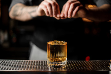Fototapeta na wymiar Bartender squeezes lemon rind in alcohol cocktail