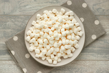 Marmalade on a saucer on a gray wooden background. View from above. Marmalade pads and polka dot pattern. Dessert in the form of white marmalade. 