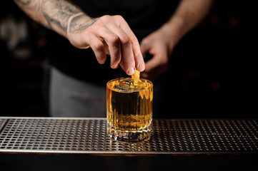 Bartender adds lemon zest in alcohol cocktail