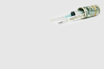 medical syringe and thermometer in a roll of dollars on a white background