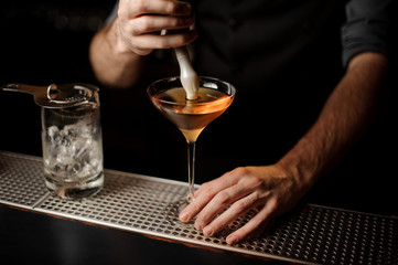 Bartender pouring an alcohol cocktail adding foam