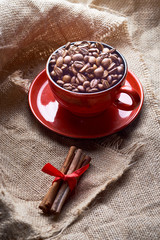 red cup with coffee beans and cinnamon sticks