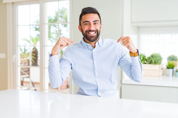 Handsome hispanic business man looking confident with smile on face, pointing oneself with fingers proud and happy.