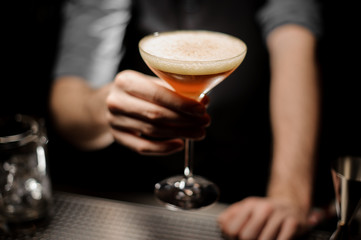 Close-up of bartender holding cocktail with foam